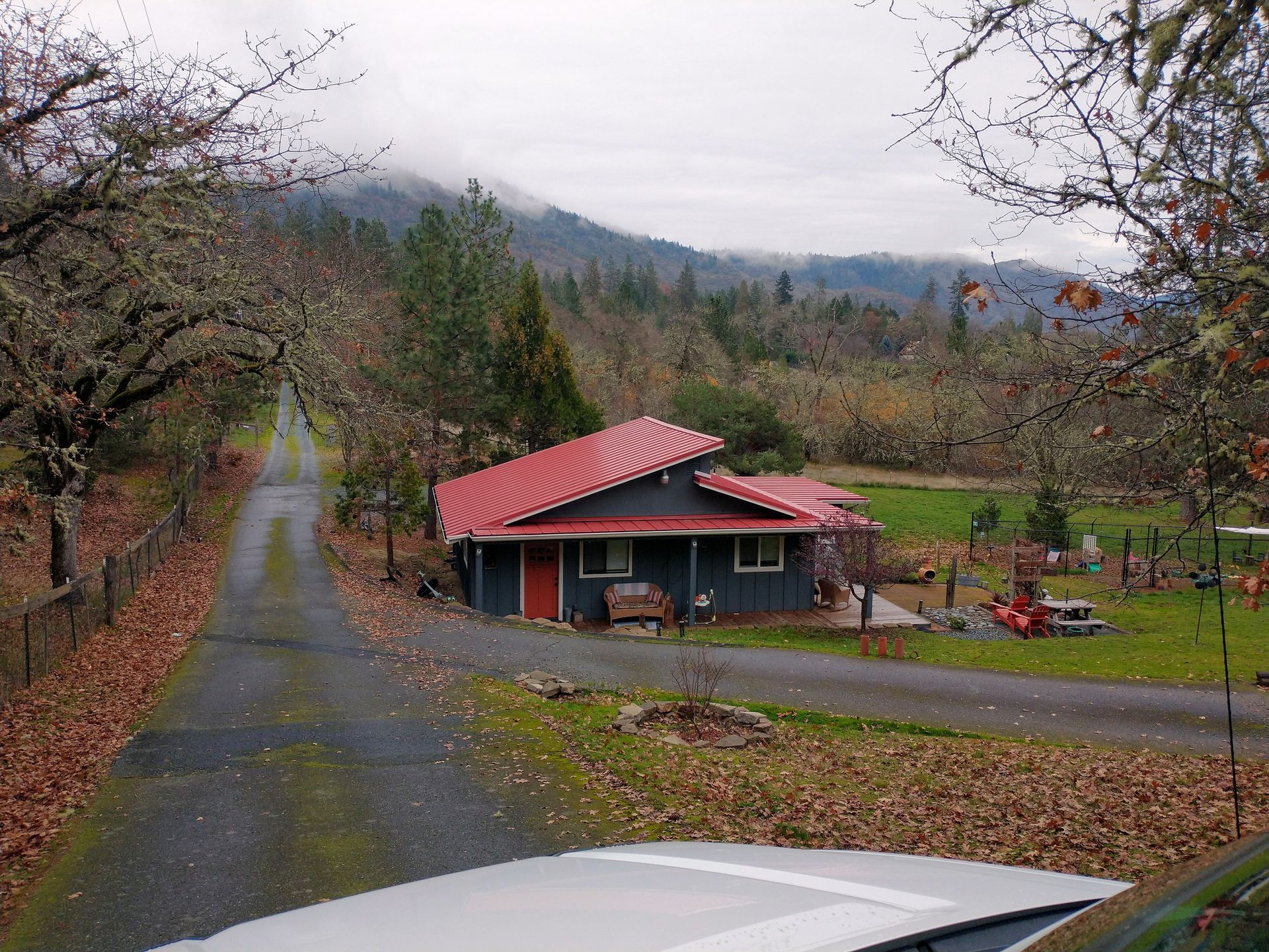 A house with a red roof is on the side of a road