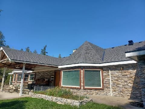 A large house with a gray roof and a stone wall.