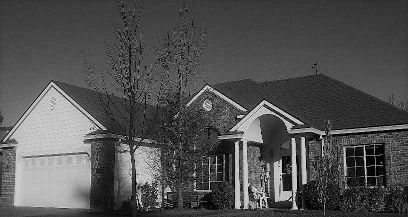 A black and white photo of a house with a porch