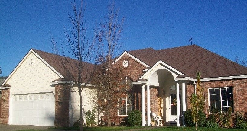 A brick house with a brown roof and white trim