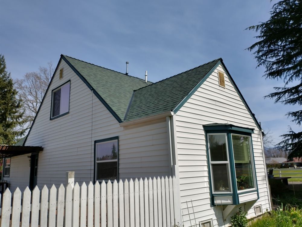 A white house with a green roof and a white picket fence