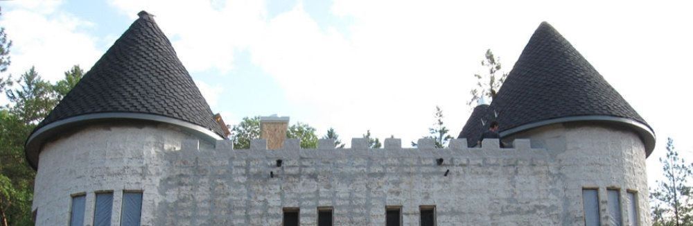 A castle with two towers is being built in the middle of a forest.