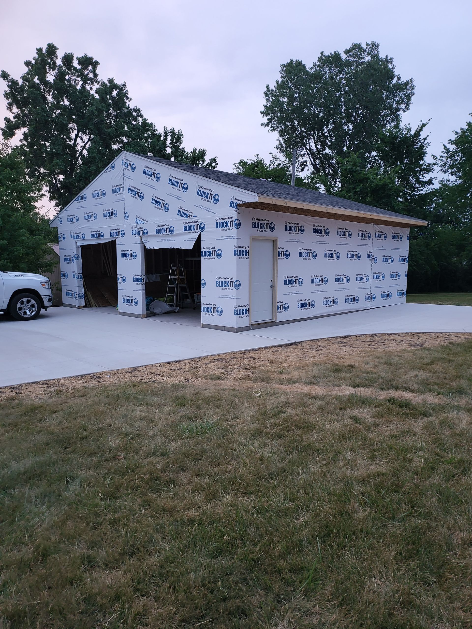 A car is parked in front of a garage that is being built.