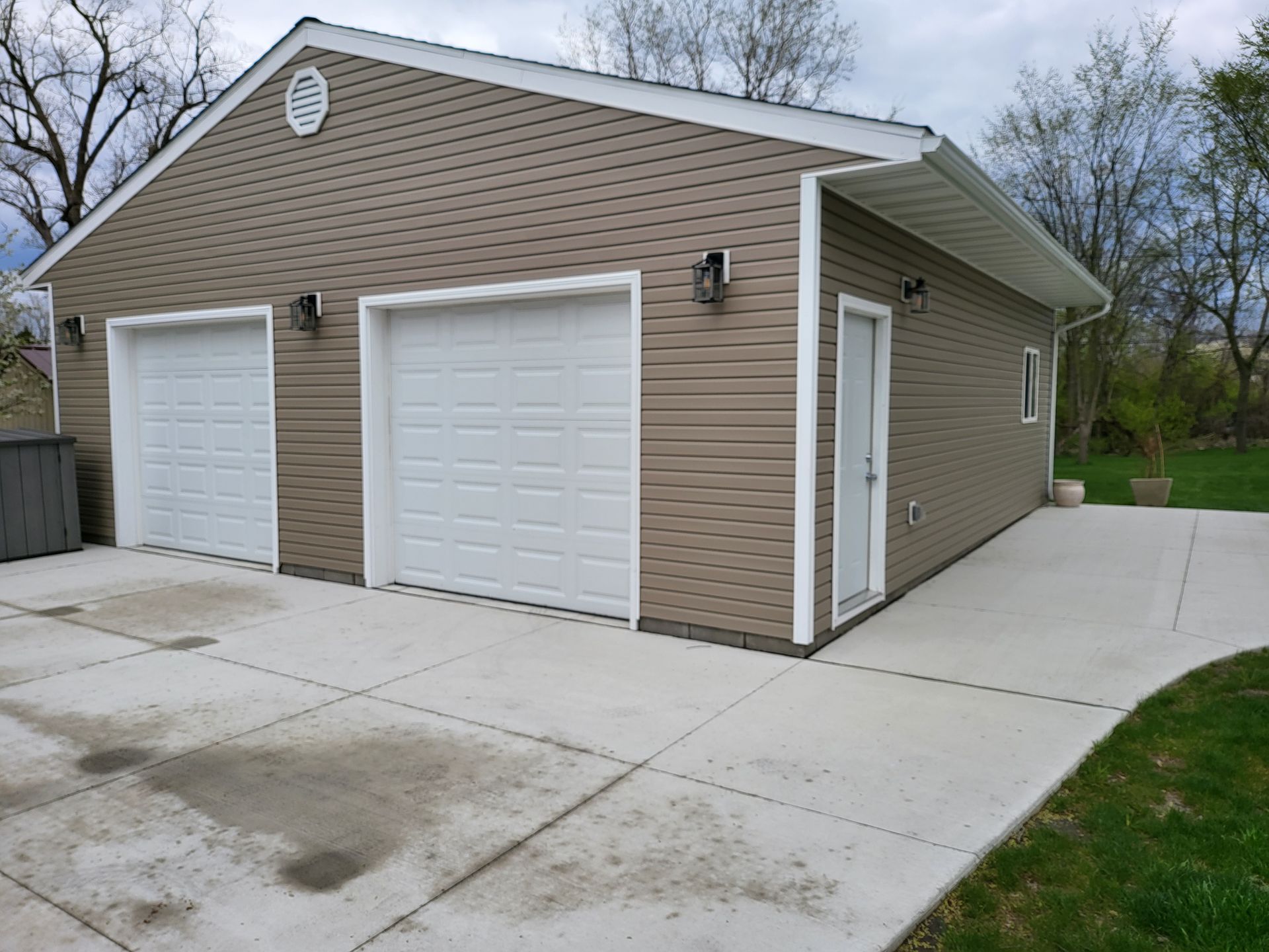 A garage with two white garage doors and a concrete driveway.