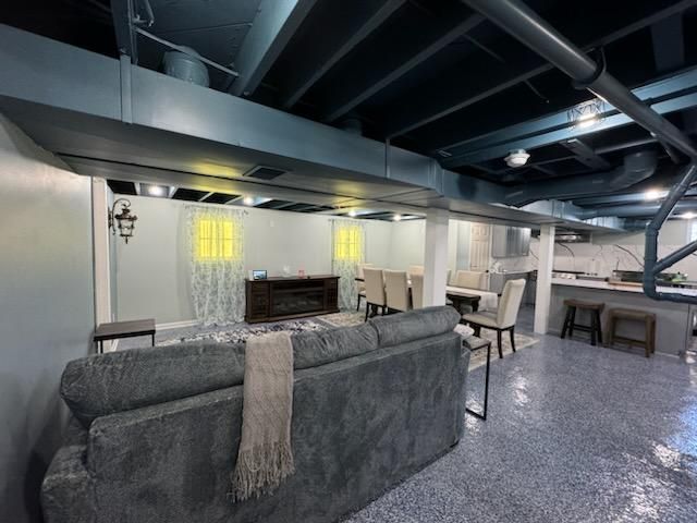 A living room in a basement with a couch and chairs.