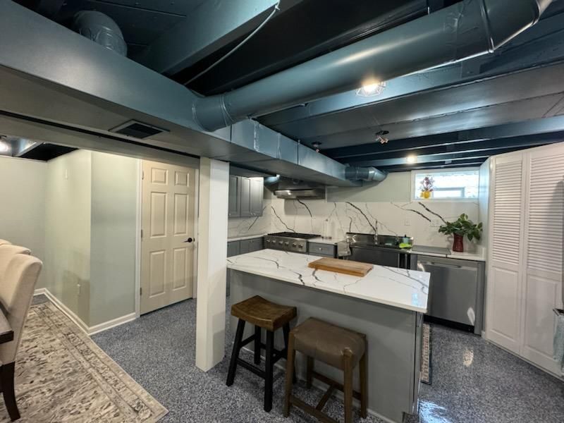 A kitchen in a basement with a large island and stools.