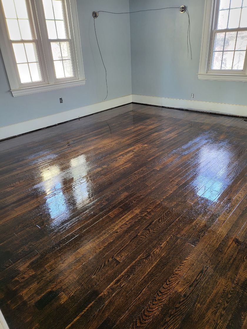 A room with a wooden floor and two windows.