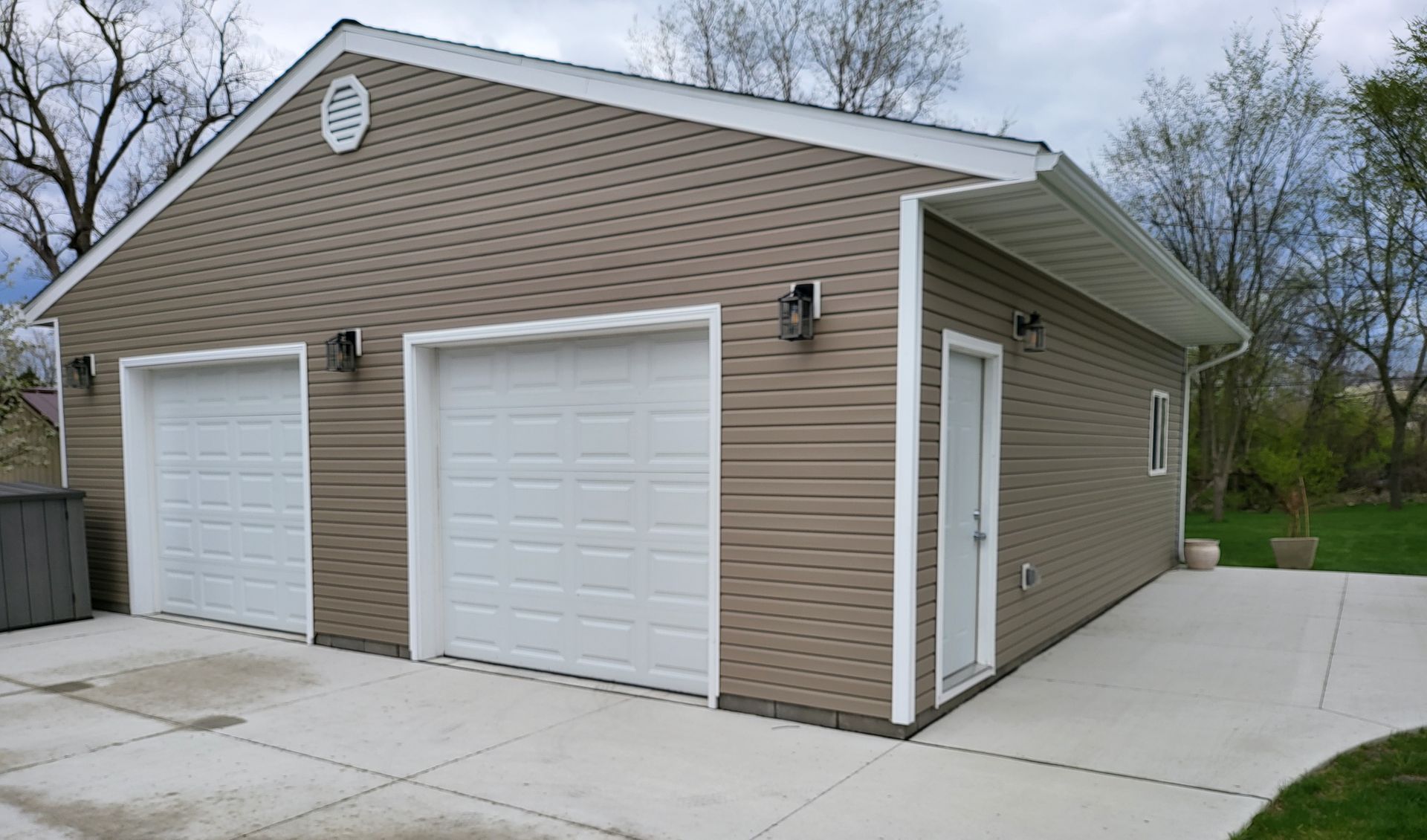 A garage with two white garage doors and a concrete driveway.