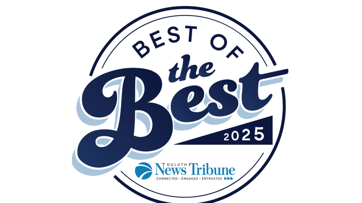 Four smiling women pose in a hallway. They wear professional attire in pastel colors.