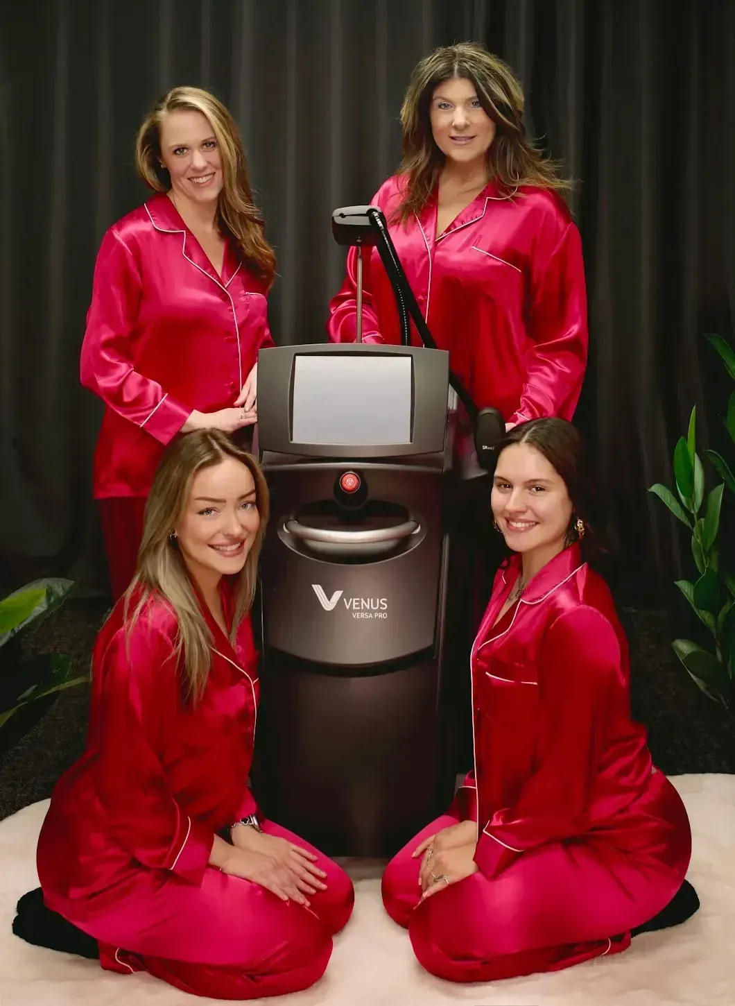 Four women in red pajamas pose near a laser machine.