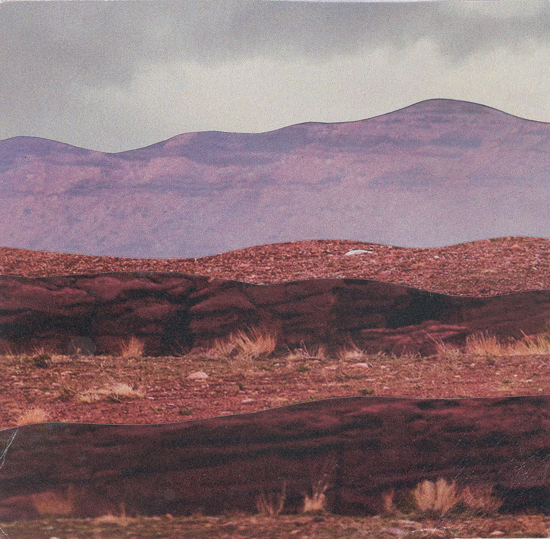 Mountains and desert landscape in shades of red, purple, and brown under a cloudy sky.