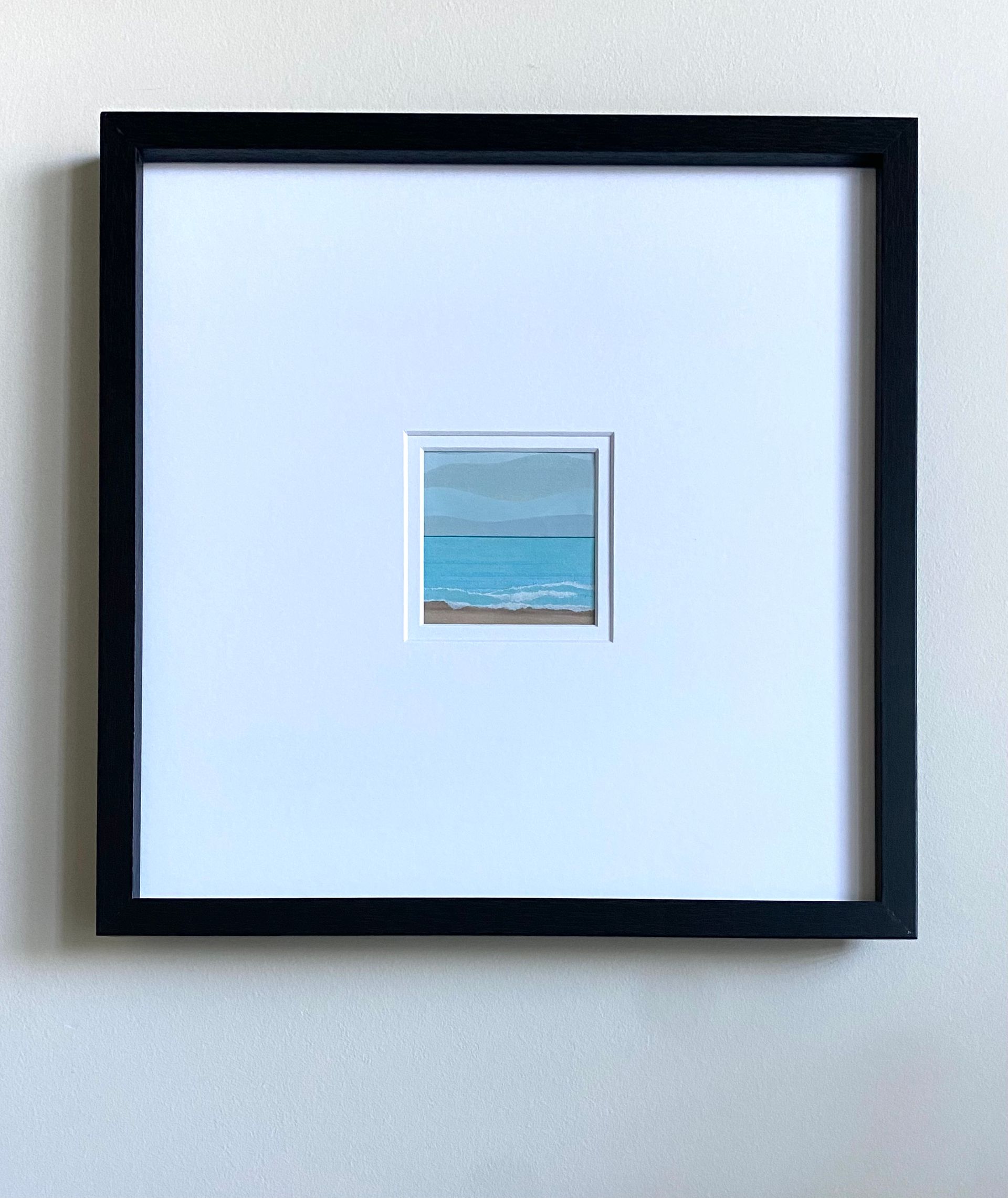Beach scene with blue ocean, foamy waves, sandy shore, and wavy blue and gray sky.