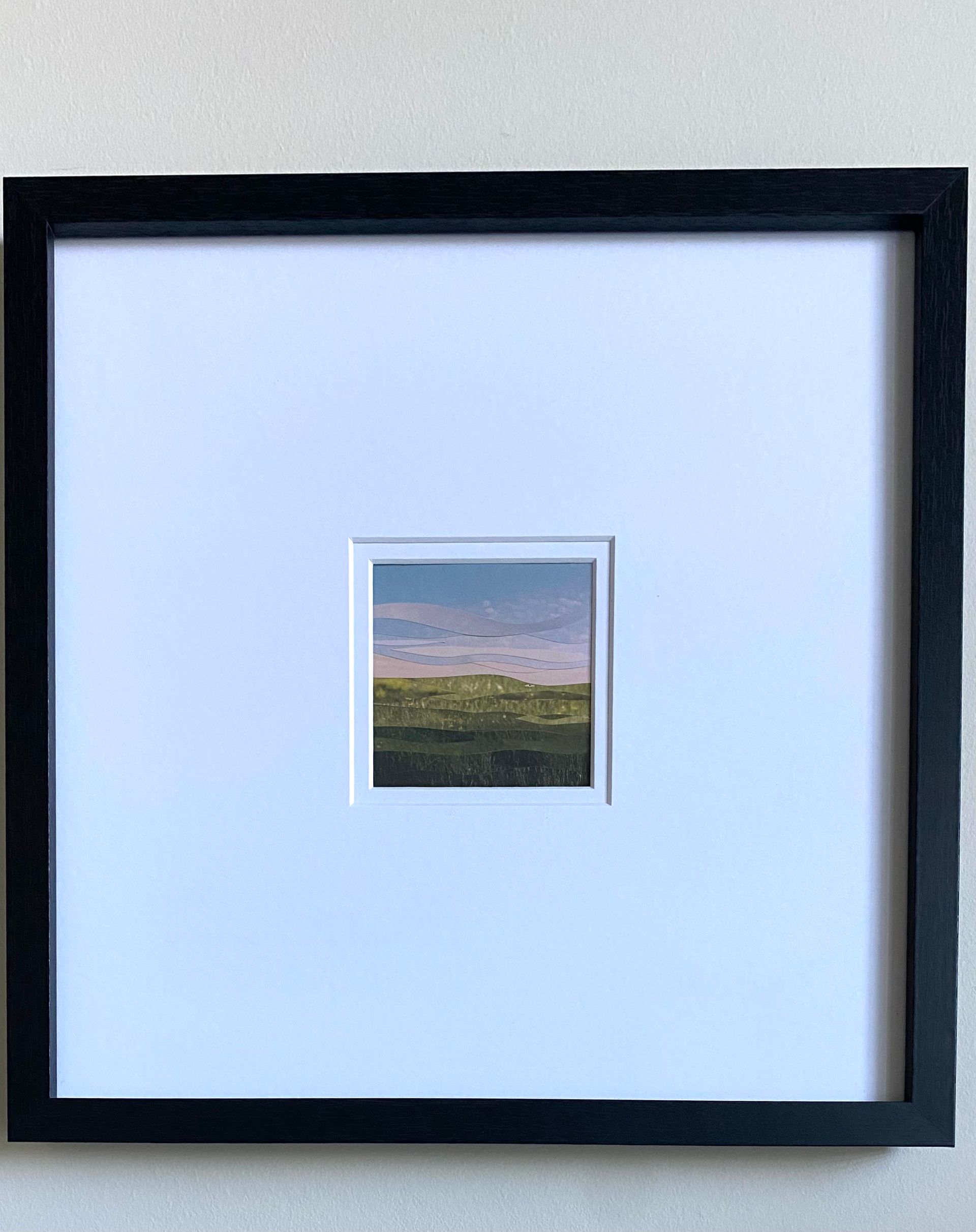 Green fields with rolling hills, a pinkish sky and blue above.