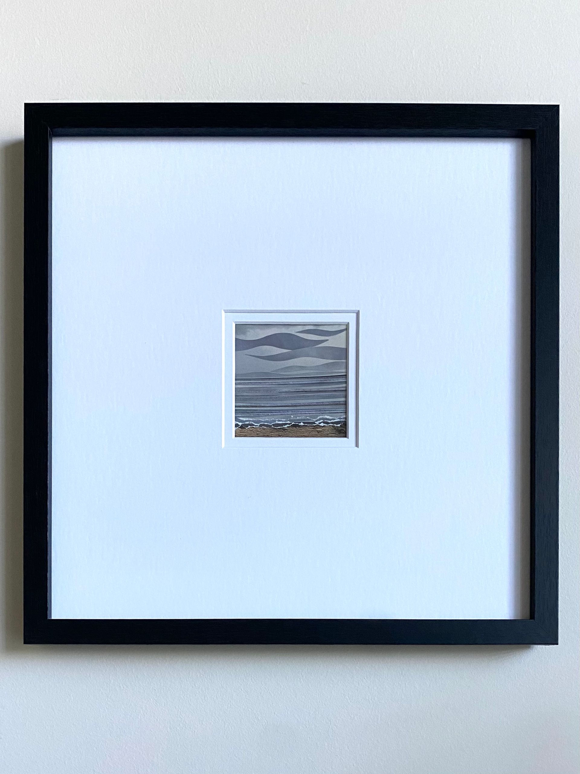 Abstract seascape: Gray waves and water, torn paper effect shoreline, tan sand, cloudy sky.