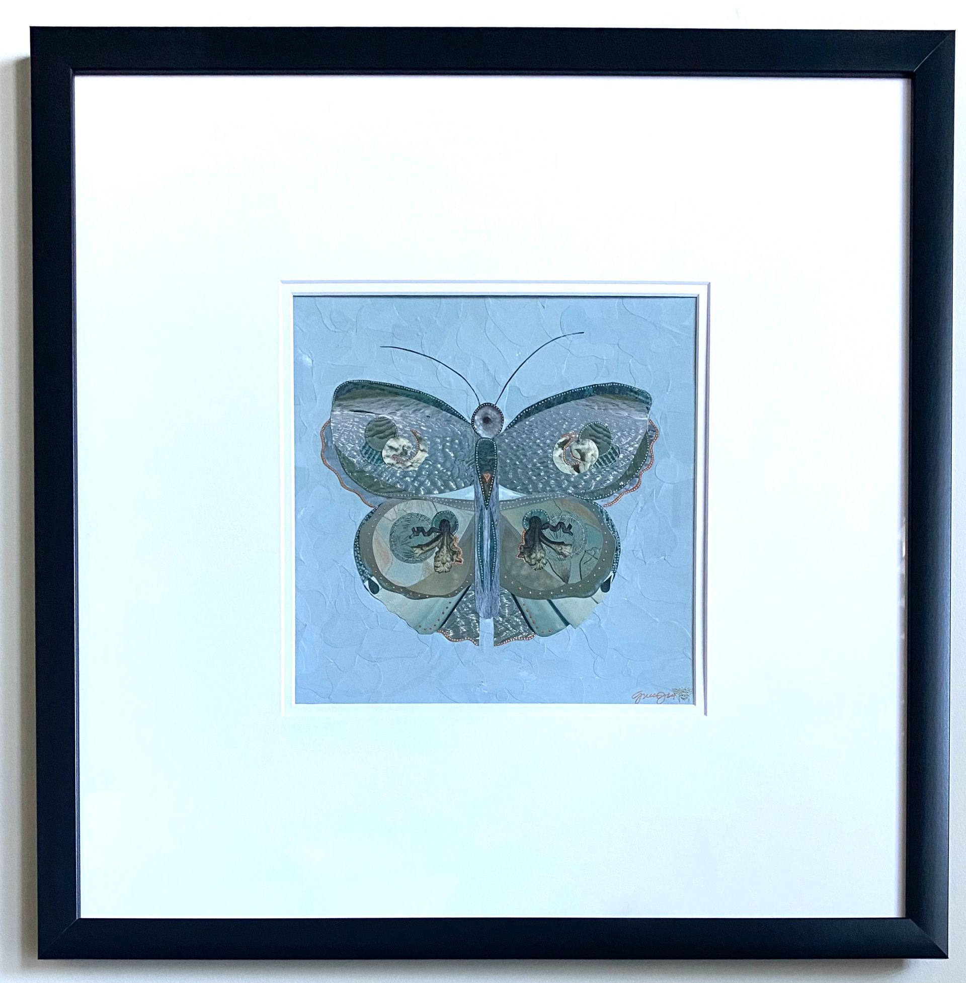 Blue butterfly collage with glitter and paper cutouts on a light blue background.