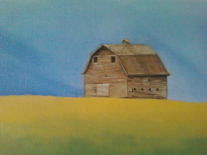 Old wooden barn on a golden field under a blue sky.