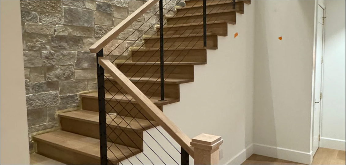 A wooden staircase with a metal railing in a hallway.