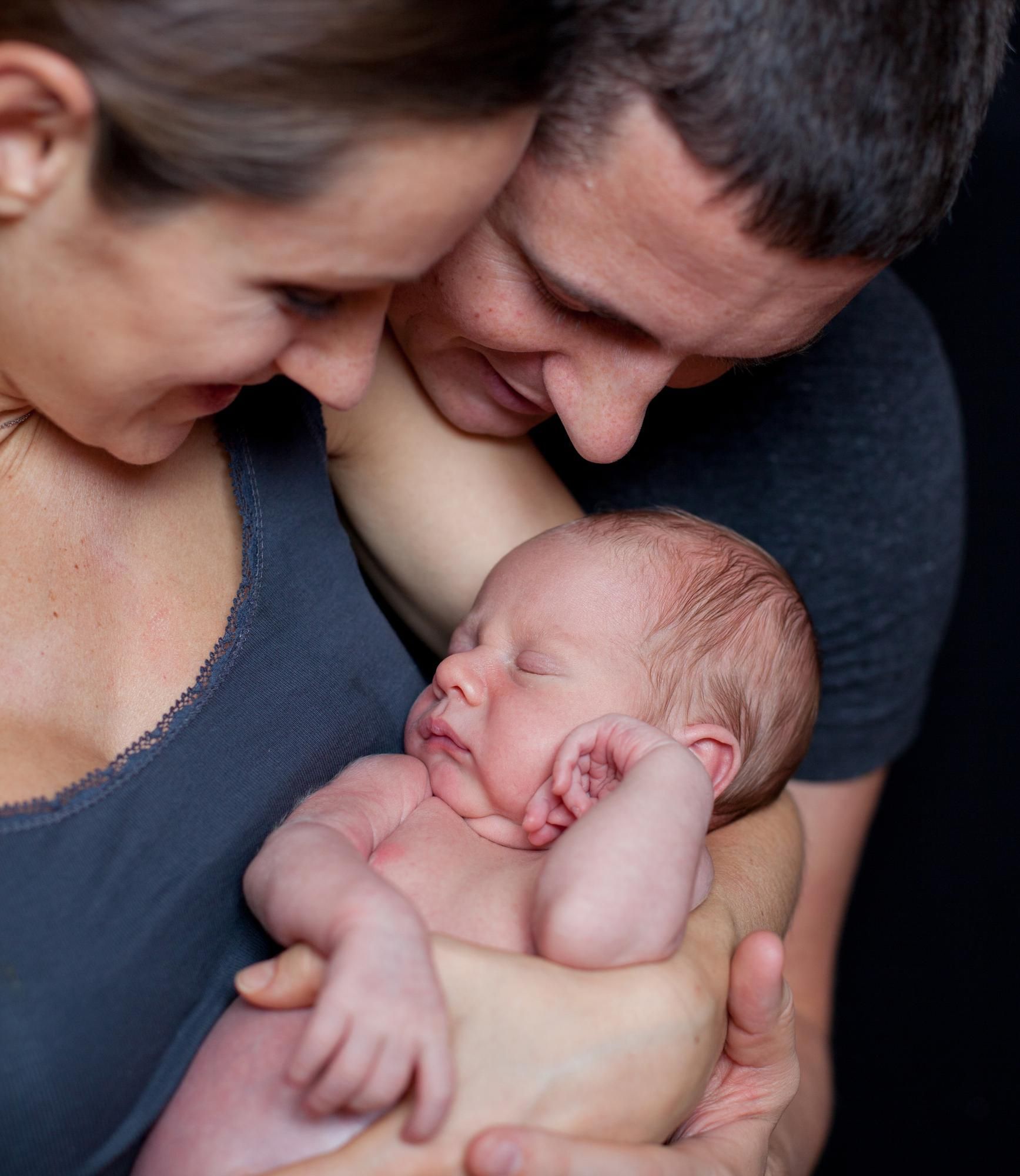 A man and a woman are holding a newborn baby