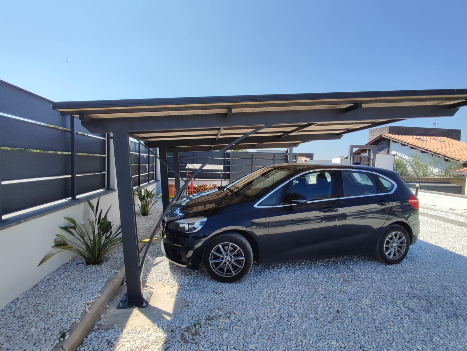 Un'auto nera è parcheggiata sotto un posto auto coperto in ferro battuto