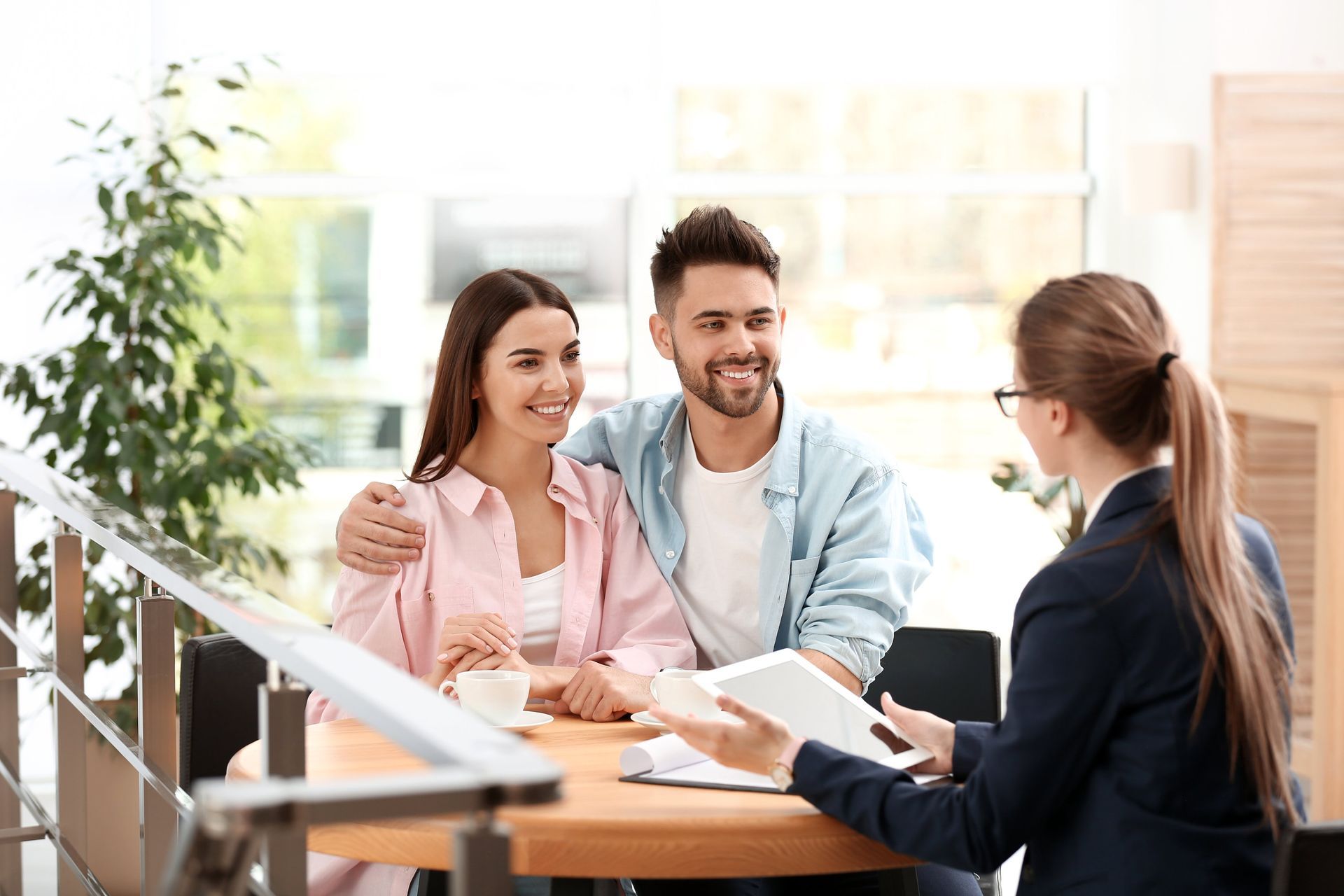Three people smiling at a table during a meeting in a bright office