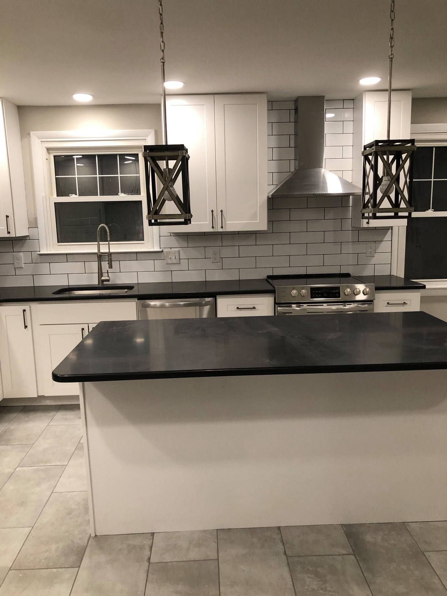 A worker installing new beige carpet in a room. The existing carpet is light gray.