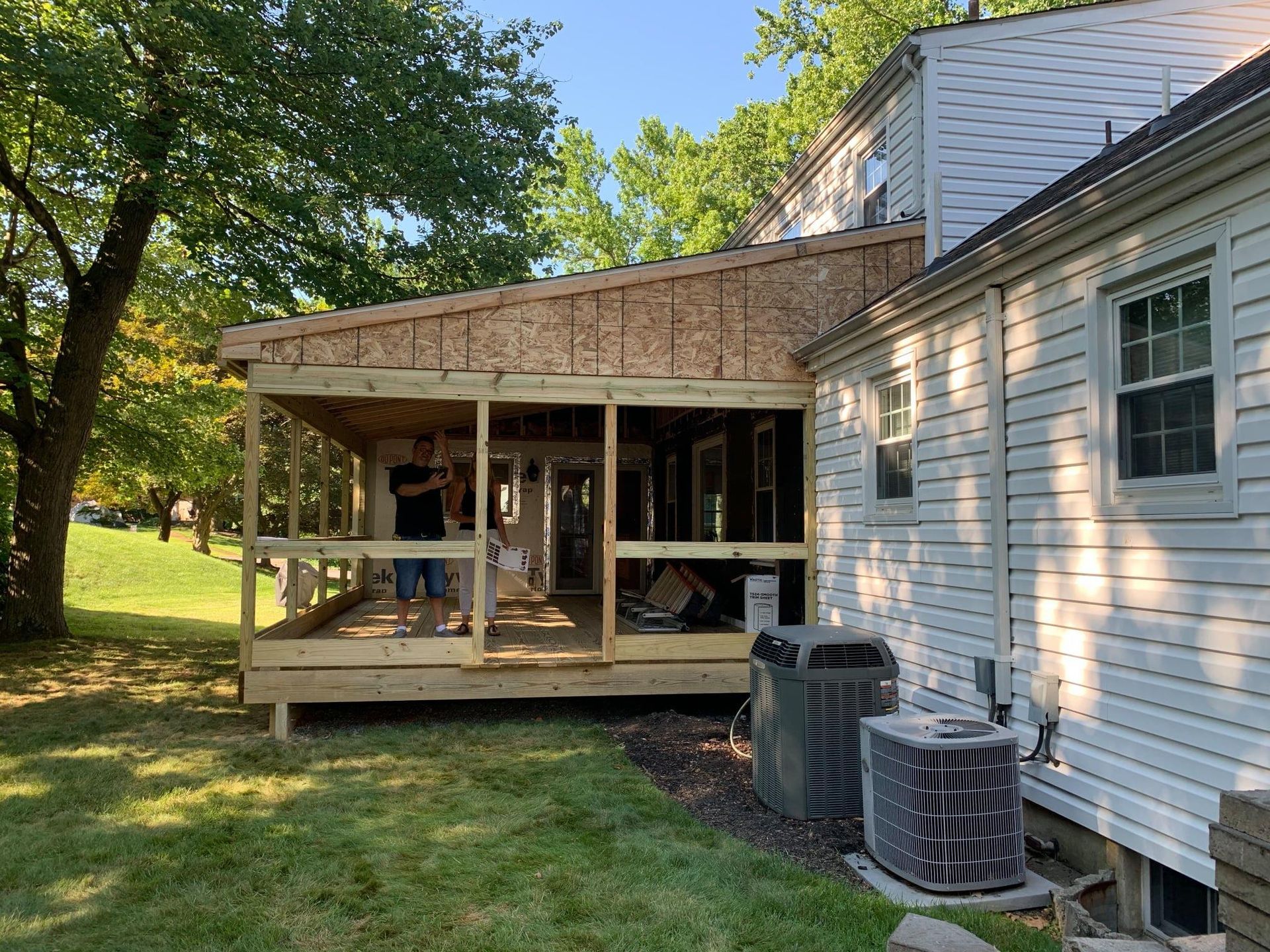 A white wall with two doors, a ceiling-mounted heater, pipes, and no smoking signs.