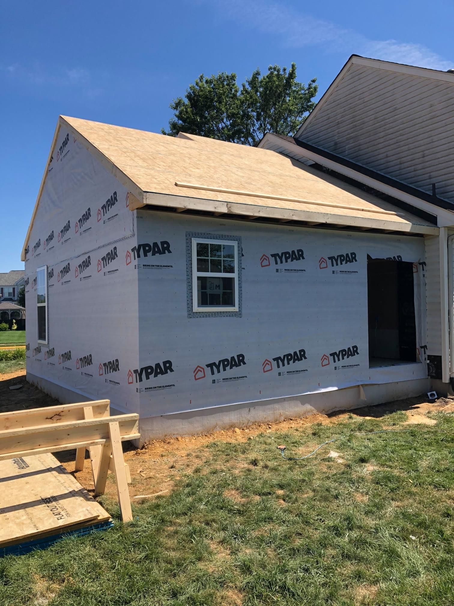 Workers smoothing fresh concrete on a patio with building materials in the background.