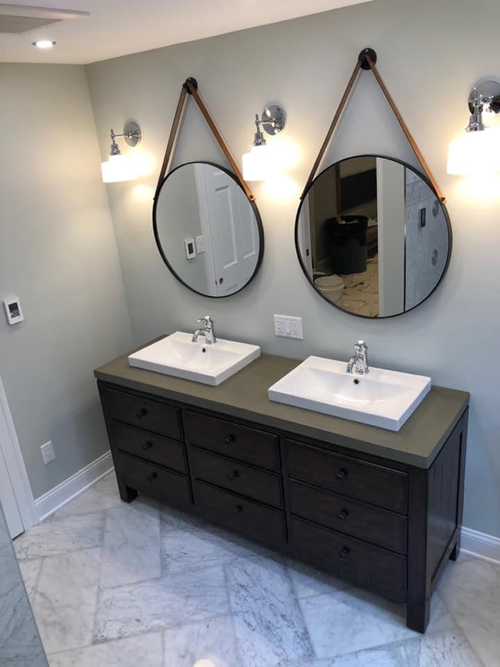 White farmhouse-style bathroom with a wall-mounted sink, toilet, and horizontal wood paneling. Black fixtures and a towel rack.