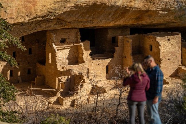 A man and a woman are standing in front of a ruined building.