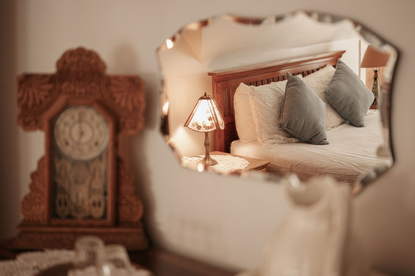 A bedroom with a bed , lamp , clock and mirror.