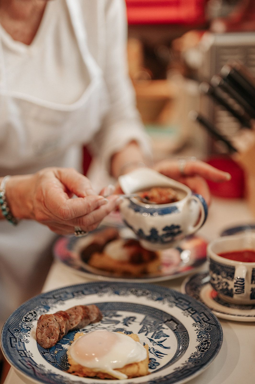 A woman is sitting at a table with plates of food and a cup of tea.