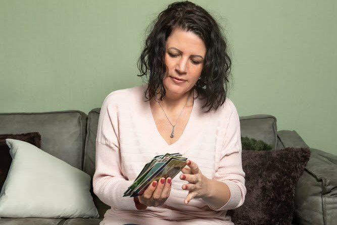 Vrouw zit op een bank en houdt een stapel kleurrijke kaarten vast, die ze vervolgens bekijkt.