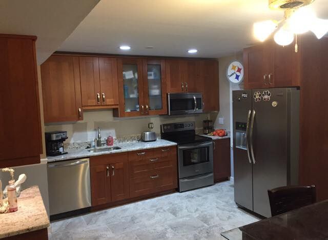 A kitchen featuring wooden cabinets, stainless steel appliances, white countertops, and a gray patterned floor.