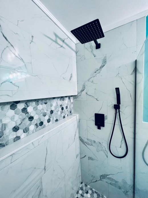 Modern shower with white marble-patterned tiles, a decorative hexagon tile accent strip, and matte black fixtures.