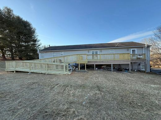 A long, wooden accessibility ramp with railings under construction along the back of a single-story house.