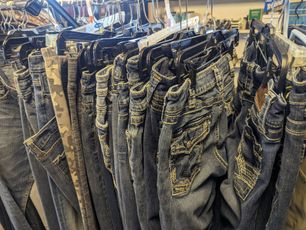 Jeans hanging on a rack, various shades of blue and tan.