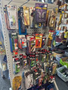 Fishing lures on a display rack in a store, various colors and shapes, many in packaging.