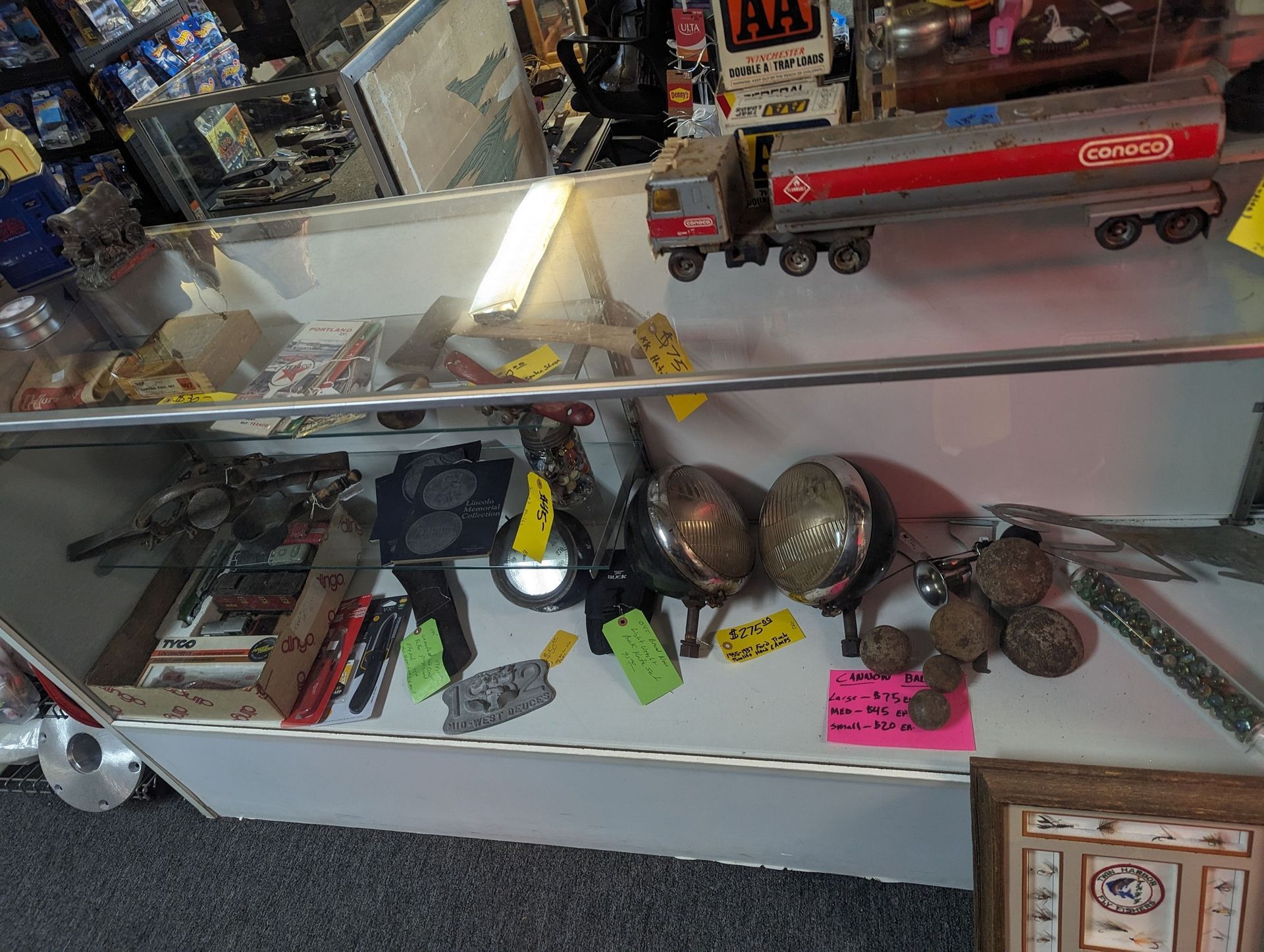 Display case with vintage items: truck, lamps, tools, and rocks, in a shop setting.