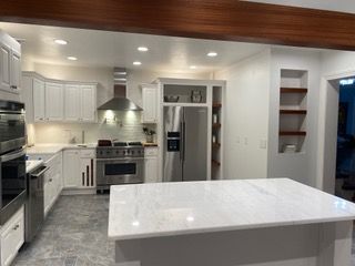 White kitchen with island, stainless appliances, and wooden accents.