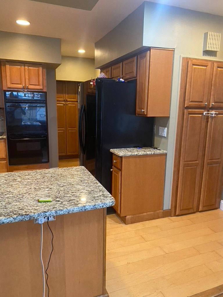 Kitchen with light wood cabinets, granite countertops, and black appliances.