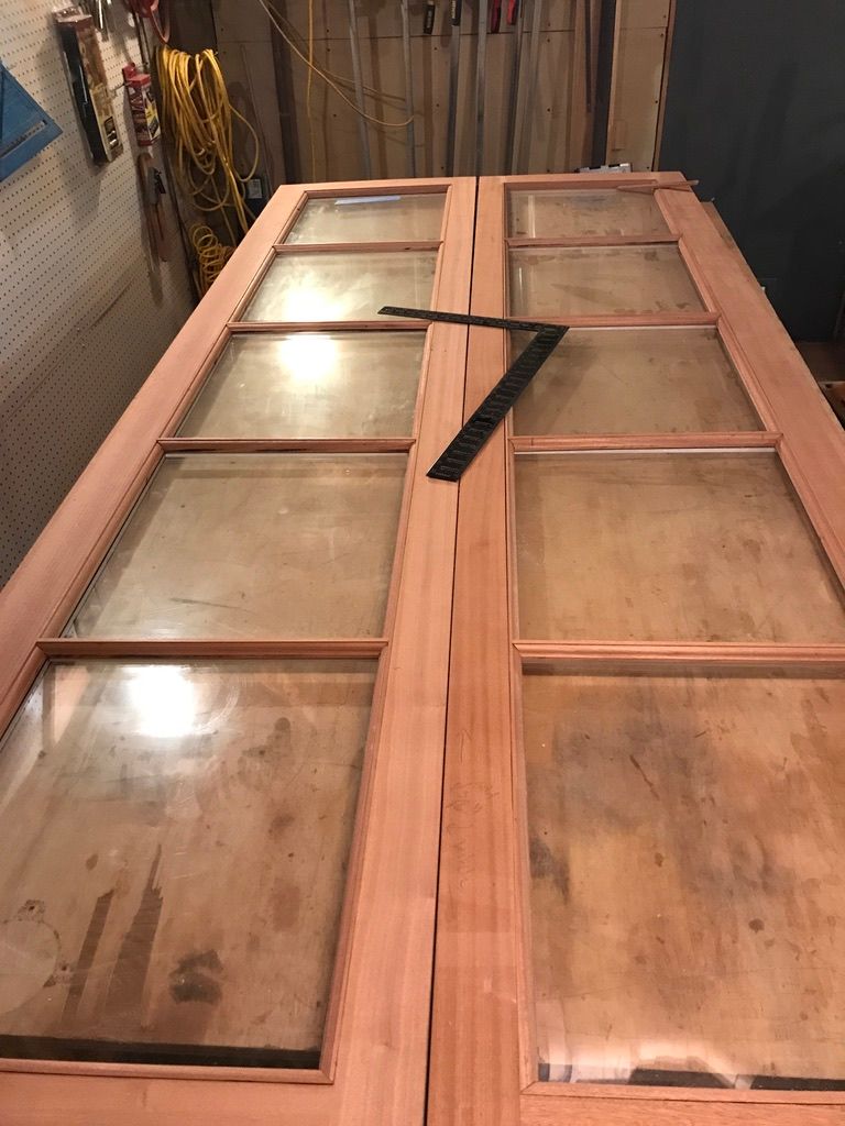 Two wooden door panels with glass panes, a black square ruler lies on the doors.