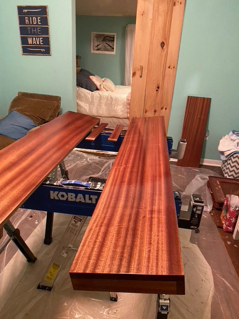 Wooden boards on a blue workbench in a room, undergoing staining.