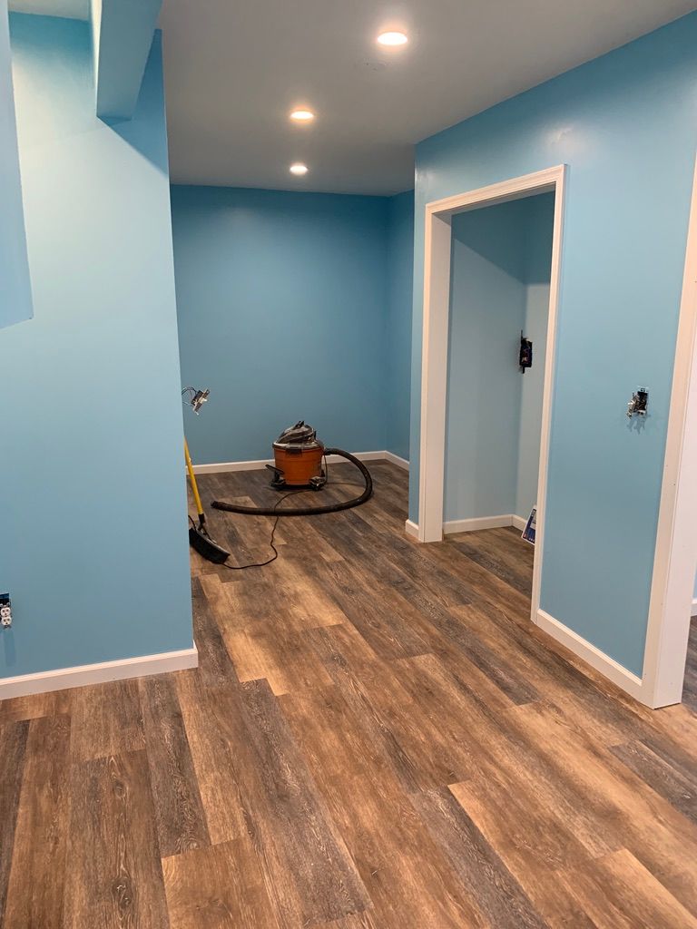 Blue-painted room with wooden floors, open doorways, and vacuum cleaner.