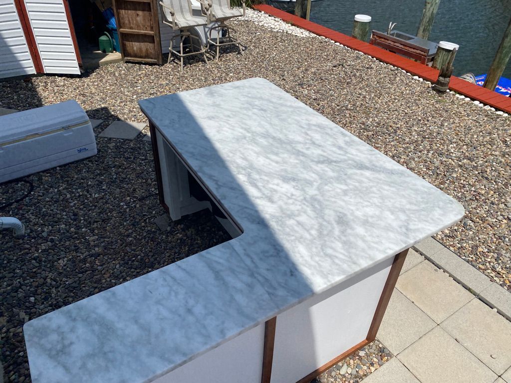 L-shaped outdoor bar with white marble countertop.