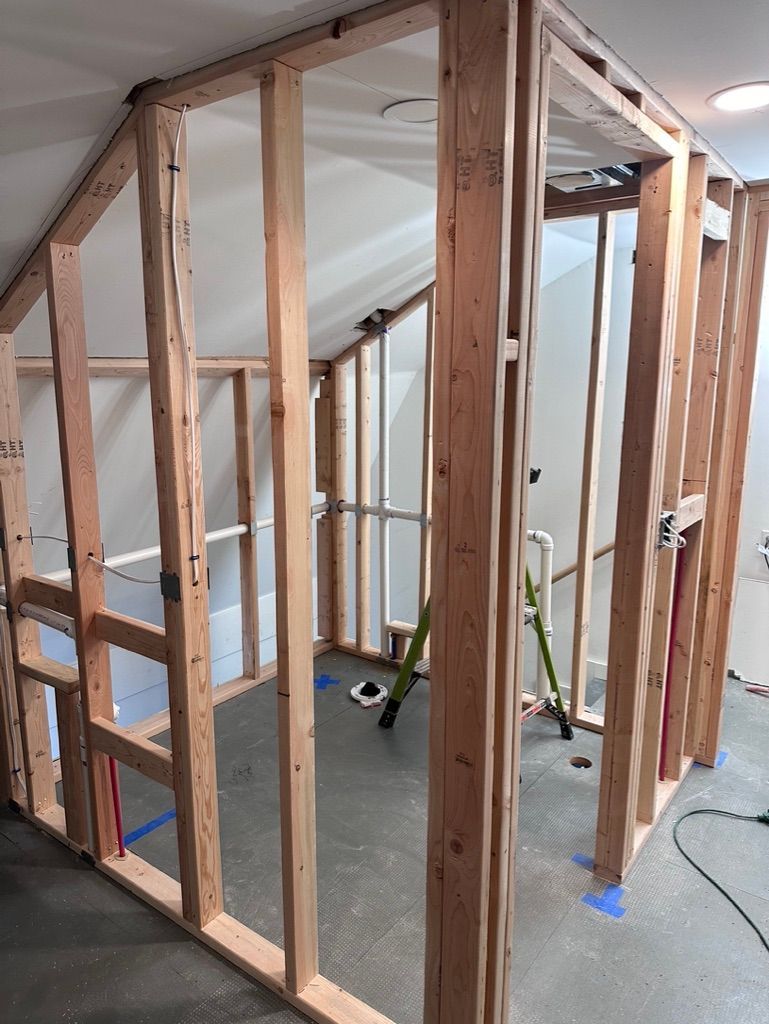 Wooden frame construction of a room in a building, with exposed studs and wiring.