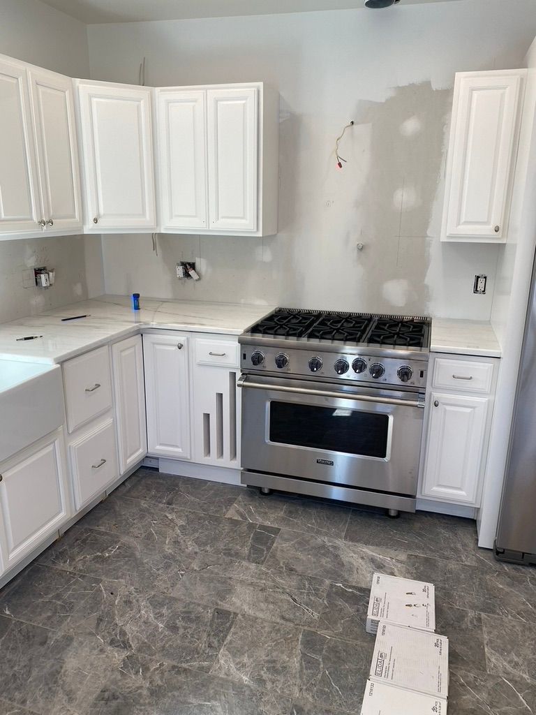 White kitchen cabinets with a stainless steel range and gray flooring.