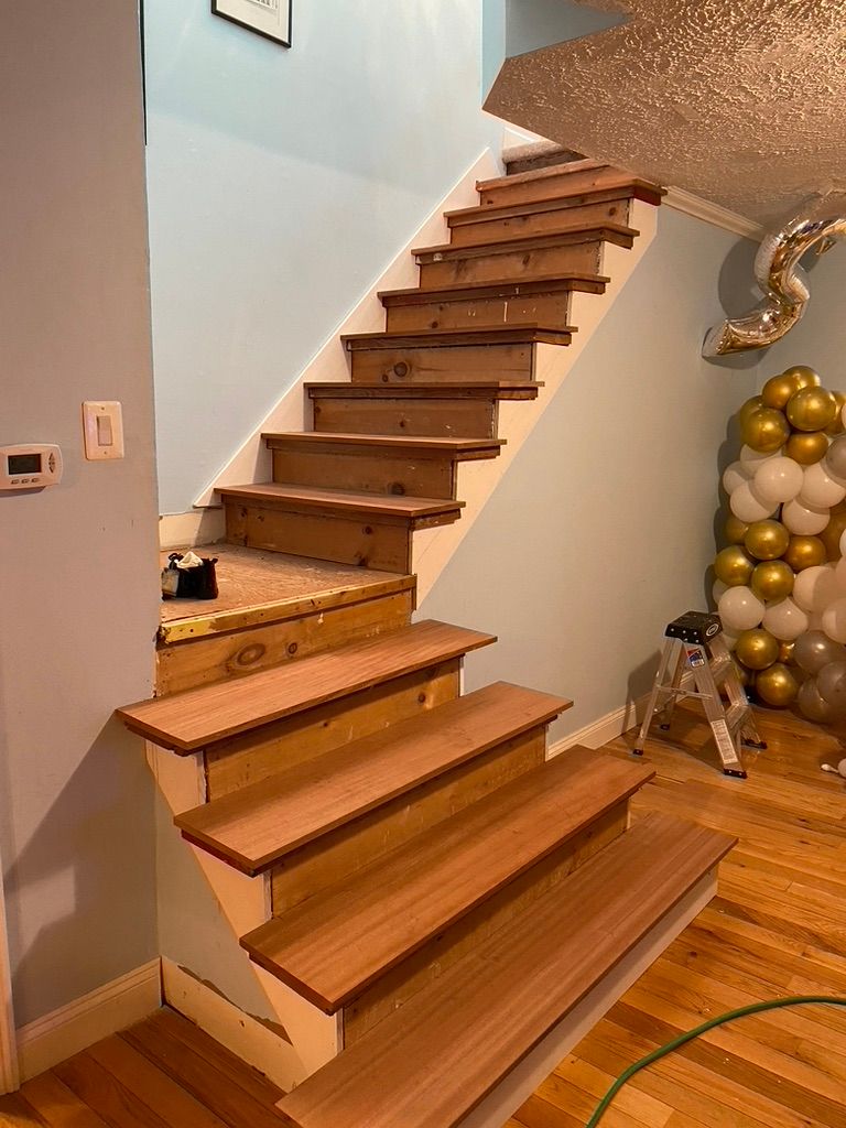 Staircase under construction; wood treads and risers installed, going up to the second floor.