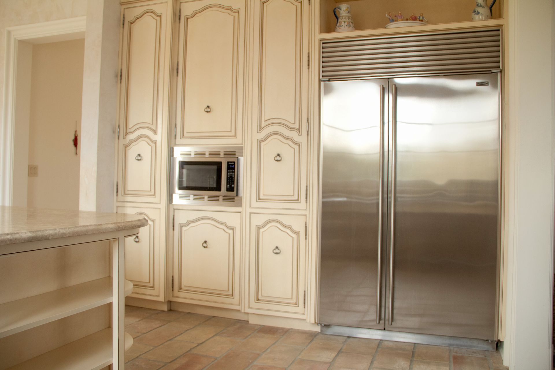 Cream-colored kitchen cabinets and stainless steel refrigerator; microwave in cabinet.