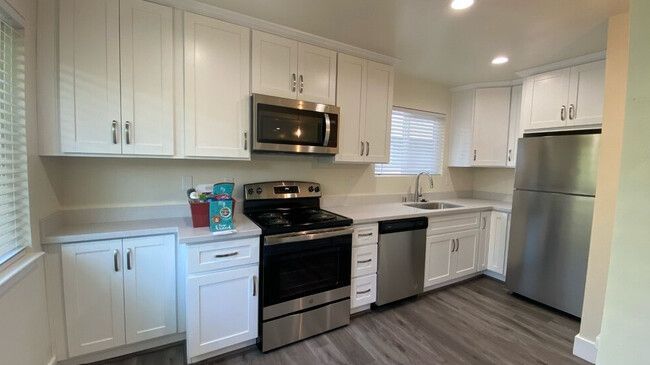 A kitchen with white cabinets , stainless steel appliances , and a refrigerator.