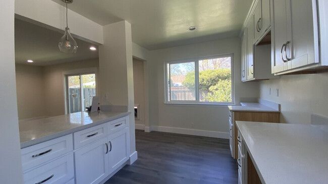 An empty kitchen with white cabinets and a large window.